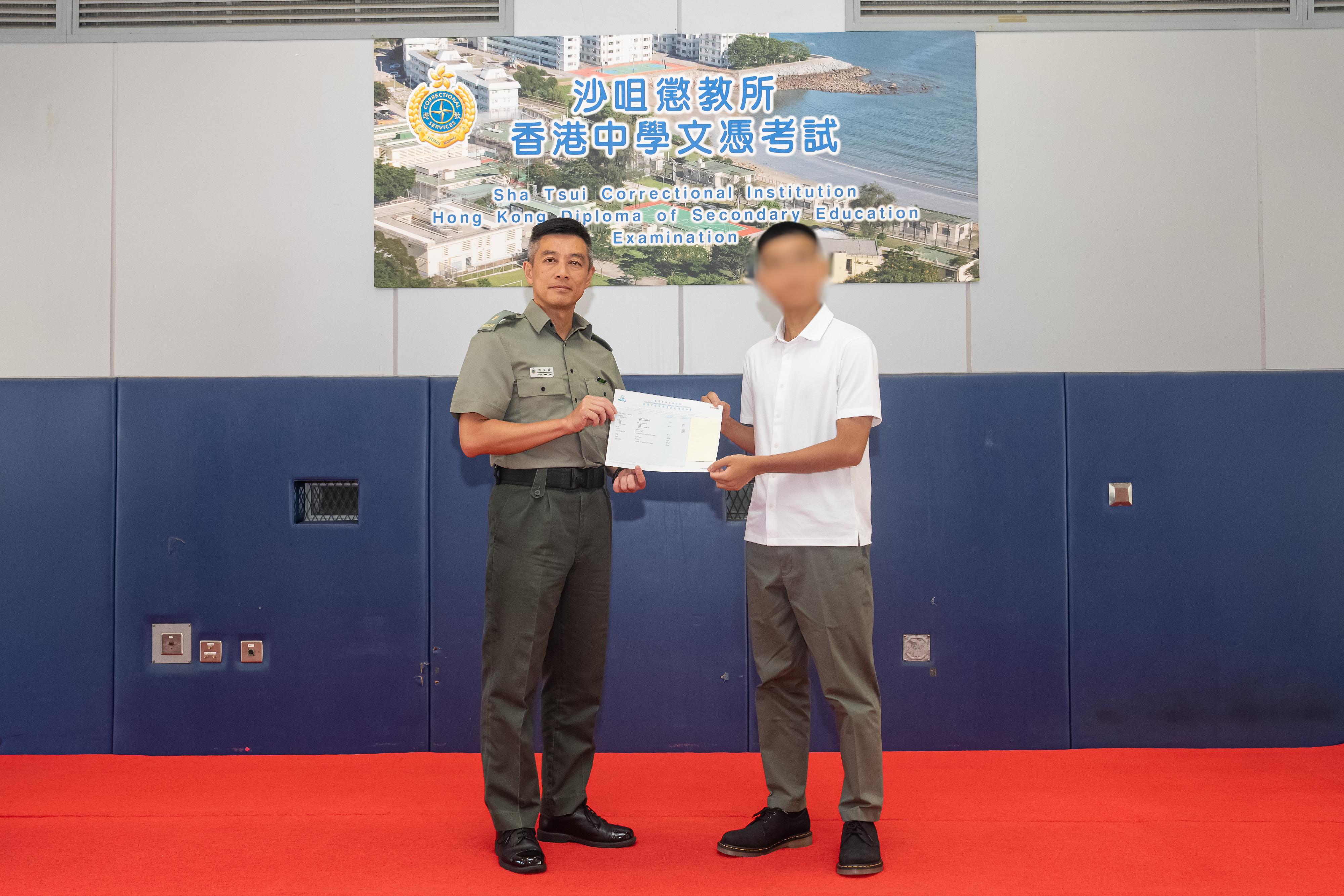 The results of the Hong Kong Diploma of Secondary Education Examination were released today (July 17). Fourteen young persons in custody enrolled in the examination this year. Photo shows the Superintendent of Sha Tsui Correctional Institution, Mr Chan Man-yat (left), presenting an examination certificate to a rehabilitated person.